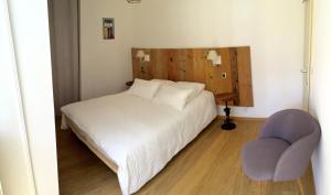 een slaapkamer met een wit bed en een stoel bij L'Appart du Vigneron in Turckheim