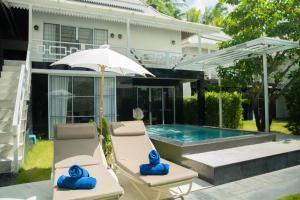 a pair of chairs and an umbrella next to a swimming pool at Phangan Cove Pool Villas in Srithanu