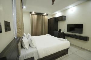 a bedroom with a white bed and a flat screen tv at Time Square Inn in Erāttupetta