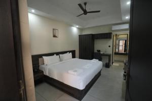a bedroom with a large white bed with a ceiling fan at Time Square Inn in Erāttupetta +14 photos