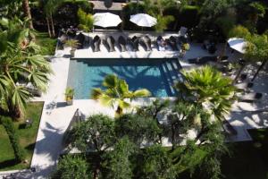 Una vista aérea de una piscina con palmeras. en GOLDEN TULIP CANNES HOTEL de PARIS, en Cannes