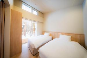 zwei Betten in einem Zimmer mit Fenster in der Unterkunft Mimi Hakuba by Jade Villa in Hakuba