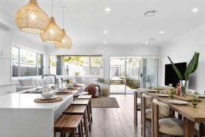 eine Küche und ein Wohnzimmer mit Holztischen und Stühlen in der Unterkunft Mare Mio Callala Beach Jervis Bay in Callala Beach