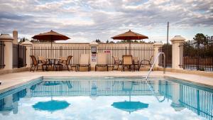 a swimming pool with chairs and tables and umbrellas at Country Inn & Suites by Radisson, Midway - Tallahassee West in Midway