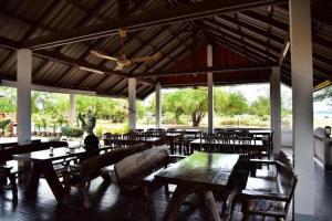 een restaurant met houten tafels en stoelen en een plafond bij Little Home Beach in Ban Khok Rak