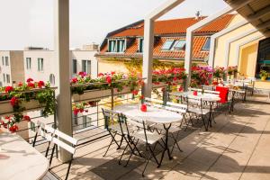 eine Terrasse mit Tischen und Stühlen auf einem Balkon mit Blumen in der Unterkunft Mikon Eastgate Hotel - City Centre in Berlin