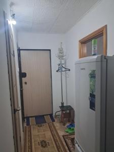 a kitchen with a refrigerator and a door in a room at 1 комн квартира рн Сазда БЦ МИР в Центре in Aktobe