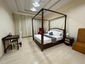 a bedroom with a canopy bed and a desk at Owls Oasis Kaziranga in Kāziranga