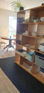 a wooden book shelf with dishes on it with a table at Stillpoint Retreat in Motungarara