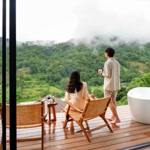 un uomo e una donna in piedi su un ponte con una vasca da bagno di Vianna Villas Chiangmai a Mae Rim