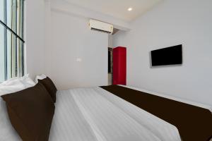 een slaapkamer met een bed en een tv aan de muur bij Super Hotel O Pukkattupady Aluva East in Cochin