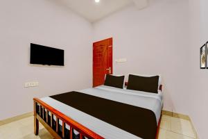 een slaapkamer met een bed en een tv aan de muur bij Super Hotel O Pukkattupady Aluva East in Cochin