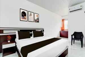 a bedroom with a white and black bed and a chair at Super Hotel O North Kalamassery in Cochin