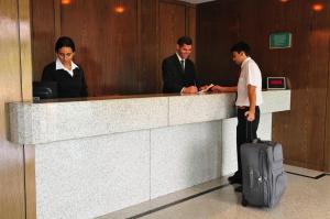 tres personas de pie en un mostrador de recepción con una maleta en Américas Gaivota Hotel en Río de Janeiro
