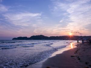 a sunset on a beach with people walking on the sand at -new-SHELL THE THIRD in Kamakura