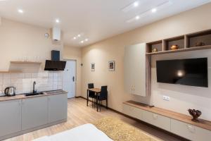 a kitchen with white cabinets and a flat screen tv at Sky by the river in Tbilisi City