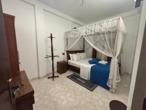 une chambre avec un lit à baldaquin et une croix dedans dans l'établissement Punida villa, à Mirissa