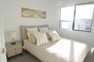 a bedroom with a bed with pillows and a window at Modern 3BR Family Townhouse & Walk to Train & Free Parking & Gated Community in Auckland