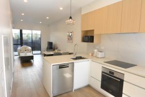 eine Küche mit weißen Schränken und ein Wohnzimmer in der Unterkunft Glen Eden Haven in Auckland