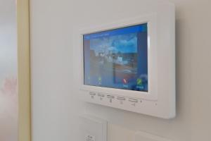 a white television is attached to a wall at Modern 3BR Family Townhouse & Walk to Train & Free Parking & Gated Community in Auckland