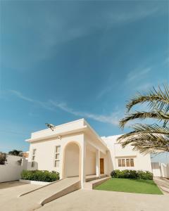 een wit huis met een palmboom ervoor bij Alesea Baroro, La Union, Private Modern Villa with Pool, Jacuzzi, Beachfront View in Balio