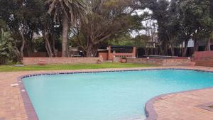 a large swimming pool in a yard with trees at Wilderness Beach Hotel in Wilderness