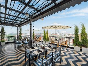 een terras met tafels, stoelen en een parasol bij HOTEL du LAC SIGNATURE in Hanoi