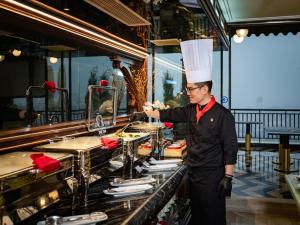 Een man met een koksmuts die eten klaarmaakt in een restaurant. bij HOTEL du LAC SIGNATURE in Hanoi +132 foto's
