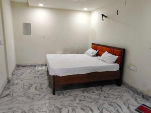 a bedroom with a bed with white sheets and a carpet at Hotel O Lake Side Inn in Gorakhpur