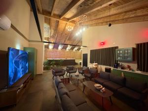 a living room with couches and a large screen tv at Alpinia in Majdal Shams