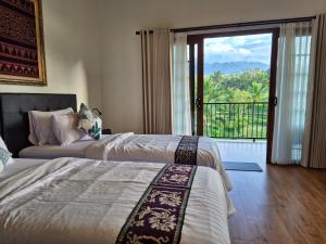 a hotel room with two beds and a balcony at A Calm Spacious Cottage with Mount Agung View in Selat