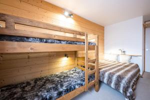 Ce lit se trouve dans un dortoir doté de 2 lits superposés et de murs en bois. dans l'établissement Appartement Valmorel, à Valmorel