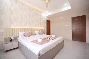 a bedroom with a large white bed with pink pillows at Hotel Qualia Oak in Hyderabad
