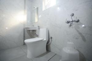 a white bathroom with a toilet and a sink at Hotel Qualia Oak in Hyderabad