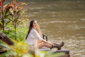 een vrouw op een bank naast een lichaam water bij River Kwai Jungle Rafts in Sai Yok +34 foto's