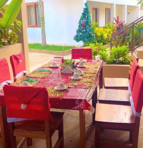 ein Esstisch mit roten Stühlen und ein Weihnachtsbaum in der Unterkunft The Dream Village in Kiwengwa