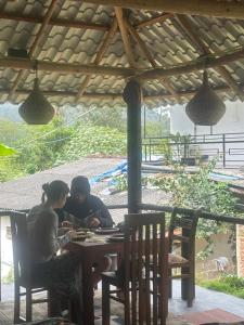 two women sitting at a table under a roof at Why Not Guset House Ella in Ella