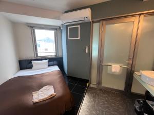 een kleine kamer met een bed en een wastafel bij Urbain Hiroshima Executive in Hiroshima