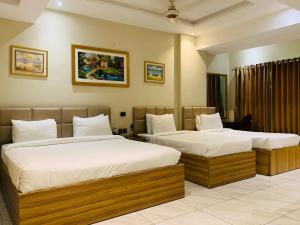 two beds in a hotel room with two beds at Hotel pearlinn karachi in Karachi