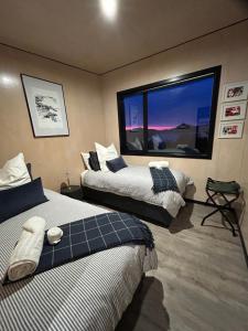 two beds in a room with a large window at Harbour Hideaway in Dunedin