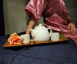 Eine Frau mit einem Tablett, auf dem eine Teekanne und Tassen stehen. in der Unterkunft Hotel Mirador in Baguio City
