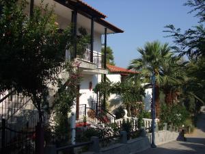 a white building with balconies and a palm tree at Studios Rosa in Agia Paraskevi