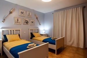 1 Schlafzimmer mit 2 Betten mit blauer und gelber Bettwäsche in der Unterkunft Villa La Perla - Cliffside Retreat in Antigua + 18 Fotos