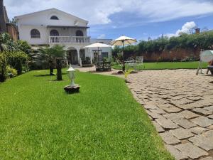 een huis met een grasveld en een oprit van kasseien bij Faly madatour GH in Antsirabe