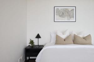 een witte slaapkamer met een bed en een nachtkastje met een schilderij bij The Outlook - 2 bed option in Newcastle