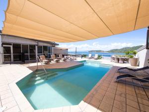 a swimming pool with an umbrella on a house at Grand Mercure Apartments Magnetic Island in Nelly Bay