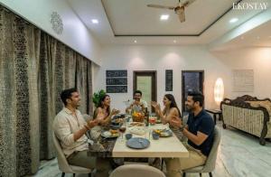 Eine Gruppe von Menschen, die um einen Tisch sitzen in der Unterkunft EKO STAY Gold- CHESTNUT VILLA in Karjat