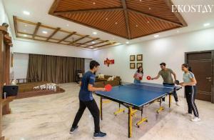 Eine Gruppe von Leuten spielt Tischtennis in einem Wohnzimmer. in der Unterkunft EKO STAY Gold- CHESTNUT VILLA in Karjat + 24 Fotos