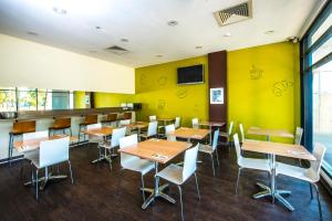 a restaurant with tables and chairs and a yellow wall at ibis Budget Sydney Olympic Park in Sydney