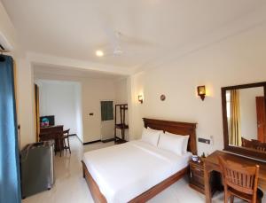 een slaapkamer met een bed, een bureau en een spiegel bij Aqua Shade Family Apartment -Weligama in Weligama